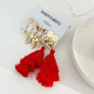 Detail van 6 paar bohemian oorbellen set met rode kwastjes en gouden bladknopjes