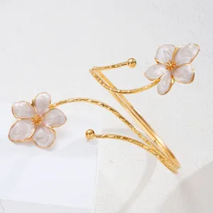 Dettaglio dei fiori in smalto bianco sul bracciale da braccio dorato regolabile