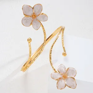 Primo piano di elegante bracciale dorato con fiori in smalto bianco effetto marmo