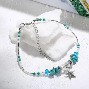Close-up view of a vintage beach anklet featuring a starfish pendant and turquoise beads.