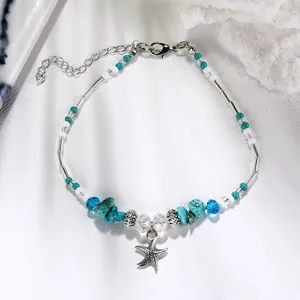 Close-up of bohemian beaded anklet featuring a silver starfish charm and turquoise accents.