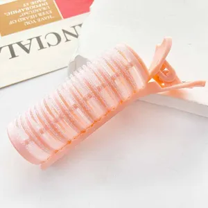 Close-up detail of a pink hair volumizing root clip resting on a magazine background