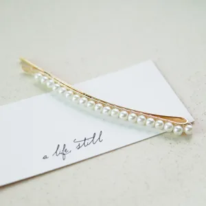 Nahaufnahme einer eleganten goldene Haarspange mit einer Reihe weißer Perlen.