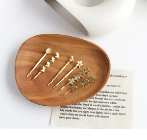 Close-up of golden metal hair clips with star and heart designs on a wooden tray
