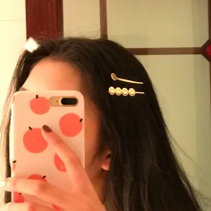 Close-up showing a model wearing gold metal smiley face hair clips for styling