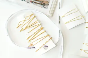 Set of gold minimalist geometric hair clips on white cardboards for hair styling