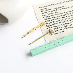 Gold metal hairpins with smiley face and star charms measured by ruler
