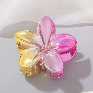 Close-up of glossy pink and gold metallic plumeria flower hair claw clip