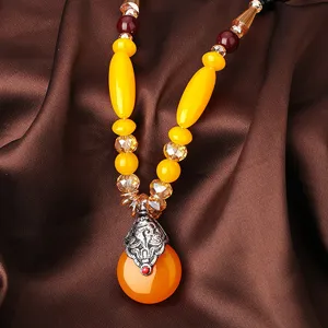Gros plan d'un collier ethnique fait main avec imitation ambre et pendentif vintage