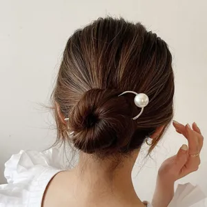 Elegant silver hair stick with a large pearl accent shown in a stylish bun hairstyle.
