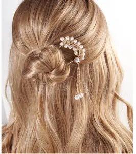 Detailed view of an elegant gold hair fork with pearls and crystals worn in a bun