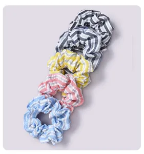 Close-up of five colorful striped fabric scrunchies arranged vertically on light background.