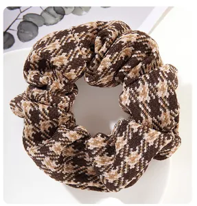 Makroansicht eines Woll-Plaid-Haargummis mit braunen und beigen Retro-Texturdetails
