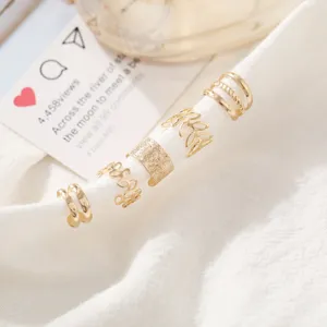 Juego de 5 earcuffs dorados minimalistas sin perforación sobre tela blanca texturizada