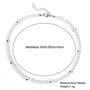 Détail du collier en perles d'imitation blanches avec perles cœur rouge et tailles