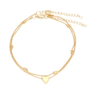 Detail shot of a minimalist double-layered golden heart anklet with polished finish
