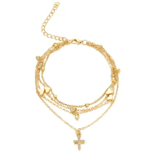 Detailed view of gold multi-layer anklet with heart charms and rhinestone cross