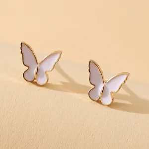 Macro view showing the elegant white enamel texture of gold-plated butterfly studs