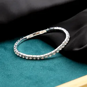 Close-up detail of a silver-tone single-row rhinestone elastic bracelet on silk background.