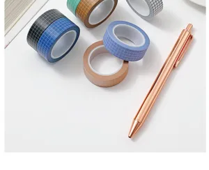 Detailed view of colorful grid washi tape rolls neatly arranged on a clean white desk surface.
