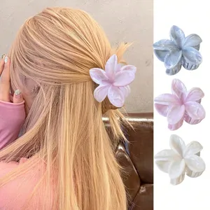 Détail d'une pince à cheveux en forme de fleur de frangipanier avec motif marbré