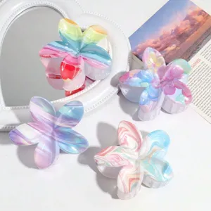Gros plan de quatre pinces à cheveux en forme de fleur de frangipanier marbrée colorée.