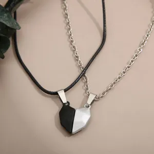 Close-up of magnetic heart-shaped pendant necklaces for couples in black and silver