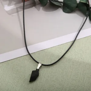 Close-up of a minimalist matte black magnetic heart pendant on a black cord necklace