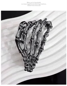 Macro view of a metallic black skeleton hand hair claw clip with a glossy finish