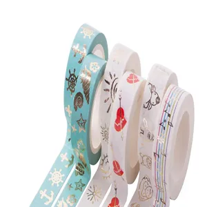 Close-up detail of decorative washi tape rolls with gold foil marine and heart patterns.