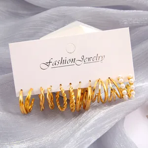 Primer plano de un set de 6 pares de pendientes dorados con diseños trenzados y perlas