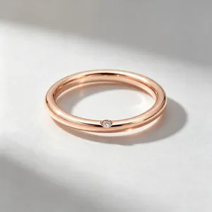 Gros plan du détail de la bague minimaliste en or rose avec sertissage de pierre délicat.