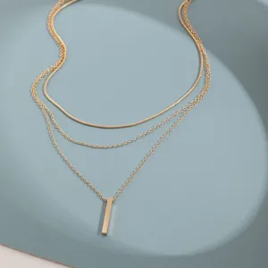 Gros plan détaillé d'un collier doré à trois rangs avec un pendentif barre verticale