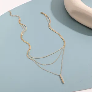 Gros plan d'un collier doré élégant à plusieurs rangs avec un pendentif barre simple