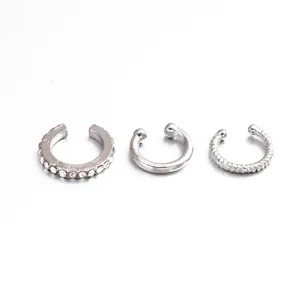 Detailed view of three silver C-shaped ear cuffs including rhinestone and twisted styles