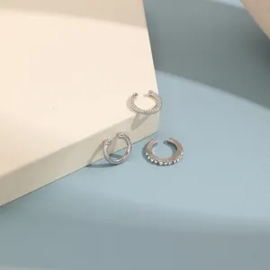 Close-up detail of three silver rhinestone C-shaped ear cuffs on minimalist background.