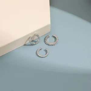 Detailed view of silver-colored rhinestone and textured ear cuff trio on blue background