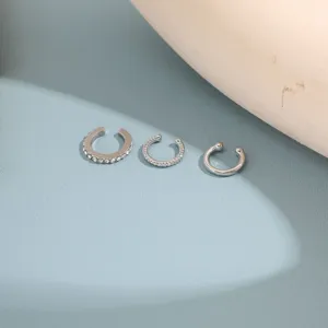 Macro detail of three silver C-shaped ear cuffs with rhinestone and textured finishes