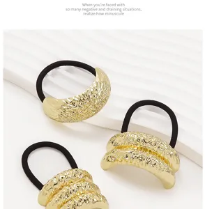 Close-up detail showing gold metallic textured elastic hair ties with minimalist geometric designs.