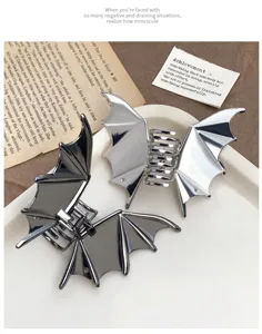 Detailed close-up view of metallic bat wing hair claw clips in silver and dark grey