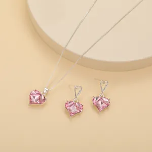 Gros plan élégant de l'ensemble collier et boucles d'oreilles cœur rose en cristal argenté