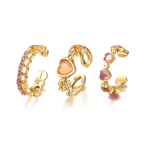 Detailed view of three gold-finish rings featuring pink heart-shaped faux cat's eye stones.