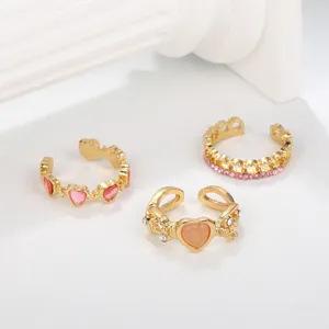 Detailed view of three gold-finished heart rings featuring pink stones and thorn designs.