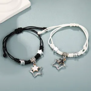 Dettaglio di braccialetti di coppia intrecciati con pendenti a stella neri e bianchi
