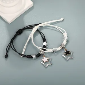 Primo piano dettagliato di braccialetti in corda intrecciata neri e bianchi con stelle
