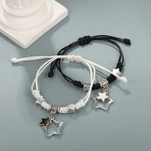 Primo piano di braccialetti intrecciati per coppia in bianco e nero con stelle.