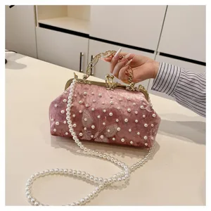 Detalle de bolso de noche vintage de terciopelo rosa con perlas y mariposa