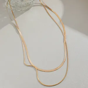 Detail showing textures of gold layered snake chain necklace on textured surface