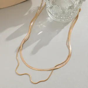 Detail of a gold double-layered snake chain necklace with elegant studio lighting