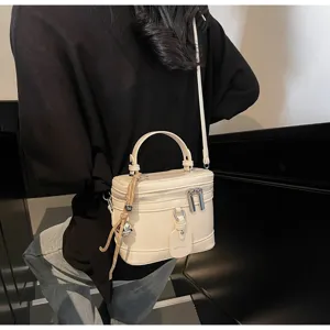 Elegant beige box handbag detail showing zipper closure and stylish decorative tag